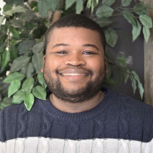 Johnny Ross is an African-American man. He has short hair, facial hair, and wears a striped sweater.